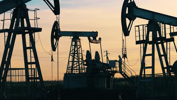 Engineer Small Figure Among Huge Oil Pumpjacks