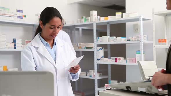 Smiling pharmacist handing paper to a customer