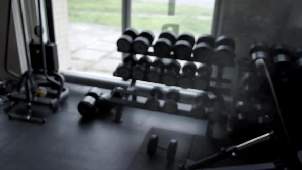 A man in a gym rubbing chalk over his hands with cotton and takes a barbell in his hands