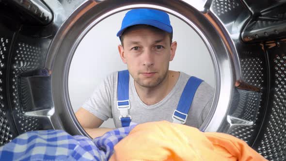 Washing machine repair worker looks inside mababan and shows class.