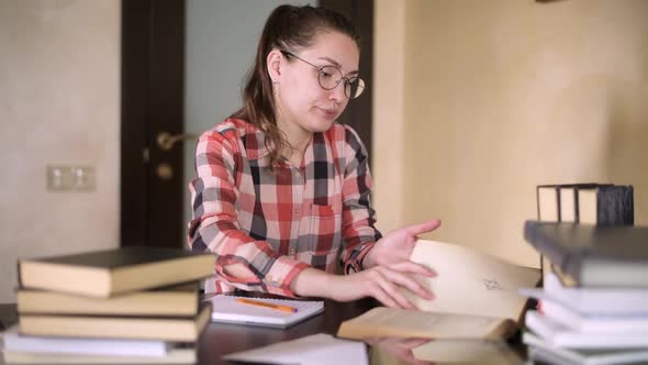 Student leafing through a book in search of material, and then outlines it