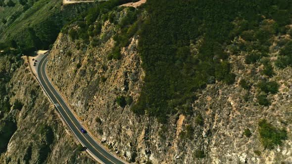 Aerial view of a road running between a mountain and the ocean