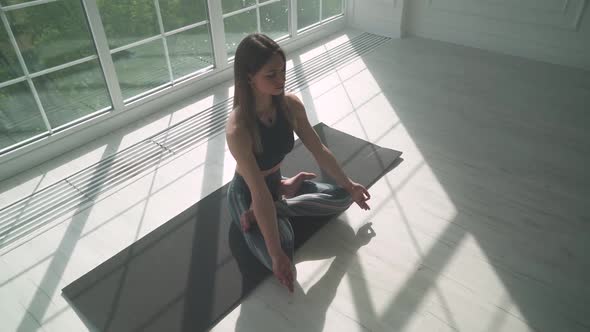 Wellness Young Female Meditates and Does Yoga a Calm Mood Relaxing in a White Room Filled with Light