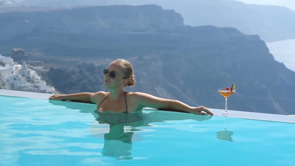 Young Woman Relaxing in the Pool with a Gorgeous View on Santorini