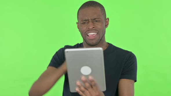 Young African Man Reacting to Loss on Tablet on Green Background