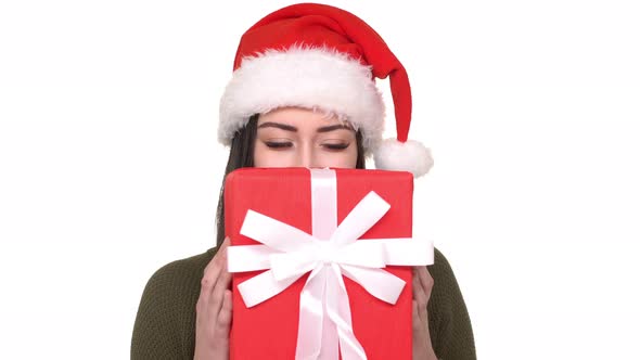 Portrait of Attractive Female with Surprise Box in Hands Wearing Santa Claus Red Hat Being Happy and