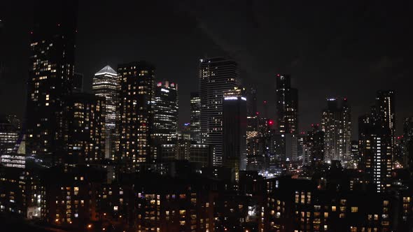 slider aerial shot of smaller Canary Wharf buildings at night full moon big city