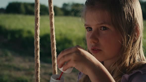 Close up of caucasian girl playing with bubbles and swinging. Shot with RED helium camera in 4K.