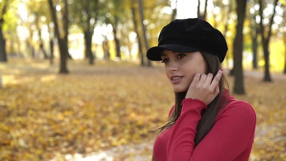 Young Brunette in Beret Posing and Flirting at Camera in Sunny Autumn Park