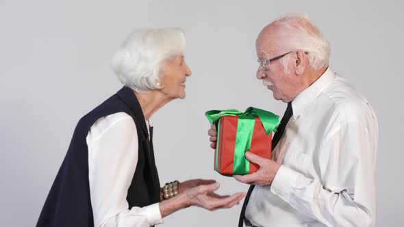 Elderly Woman Giving Present to Senior Man