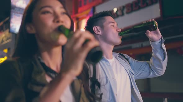 Asian attractive couple drinking alcohol and having party together at dark night on the road.