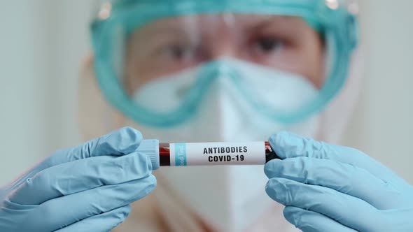 Close Up of Doctor Holding Test Tube with Covid-19 Antibodies on Bright Background.