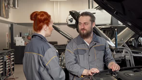 Bearded Mechanic Talking To His Female Coleague at the Automobile Workshop