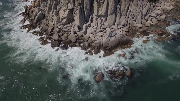 View From a Drone Vertically Down on a Stone Cape Washed By Strong Waves