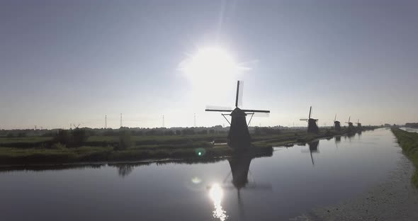 A drone shot panning right, around Dutch Windmills during sunrise