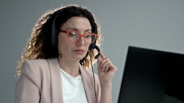 Customer Support Agent or Call Center with Headset Works on Desktop Computer While Supporting the