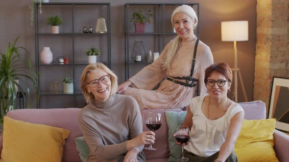 Portrait of Three Adult Women with Red Wine in Glasses at Home Party