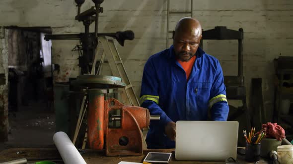 Metalsmith using laptop in workshop 4k