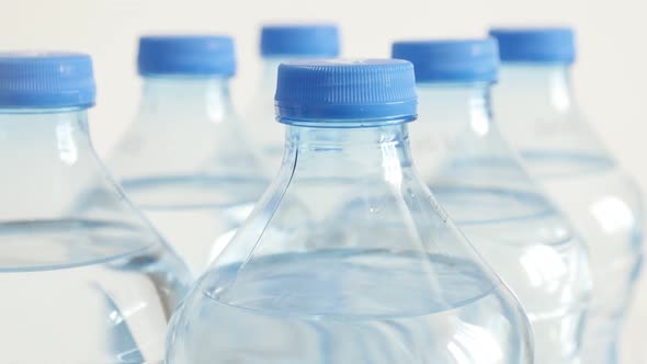 Bottled water in a row close-up 4K 2160p 30fps UltraHD tilting footage - Blue caps on PET containers