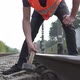 A railroad worker in a hard hat is repairing a railroad by hammering a spire with a sledgehammer. - VideoHive Item for Sale