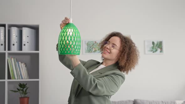 Modern Technologies Young Woman Designer is Decorating Room and Hangs 3D Printed Lamp Shade Smiles