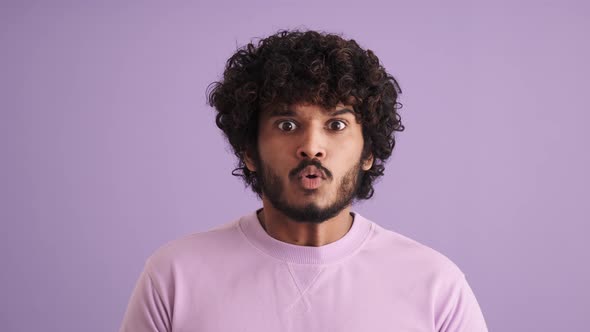 Scared curly-haired Indian man clutching his head