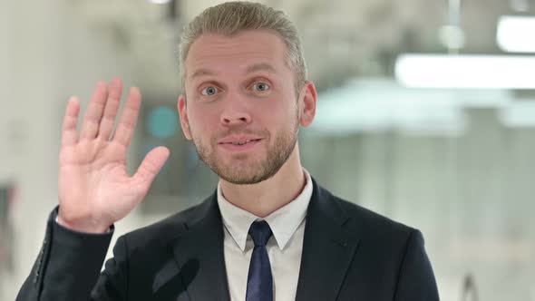 Portrait of Cheerful Businessman Waving at the Camera 