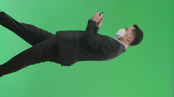 Asian Business Man Use Mobile Phone While Walking On Green Screen Chroma Key, Wear Medical Mask