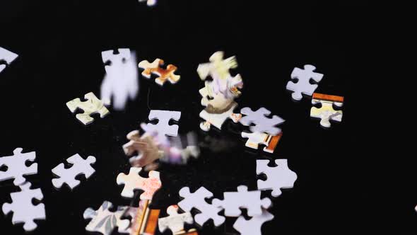 Falling puzzle pieces on a mirrored black background. Close-up. Slow motion