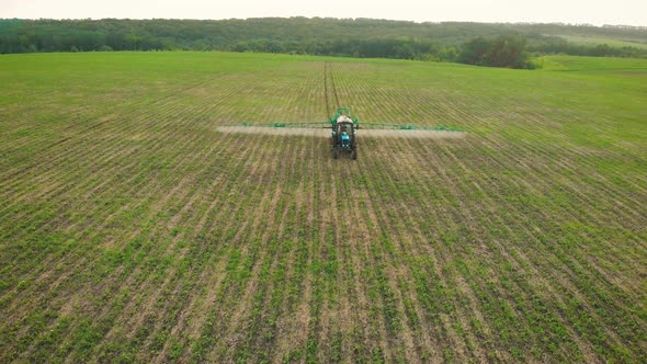 Aerial View of Farming Tractor Spraying on Field with Sprayer Herbicides and Pesticides at Sunset