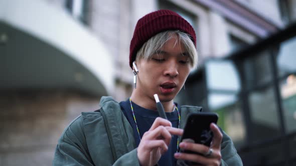 Handsome Asian man smoking and texting by phone