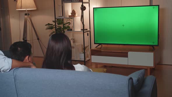 Back View Of Asian Family Watching Tv With Mock Up Green Screen At Home