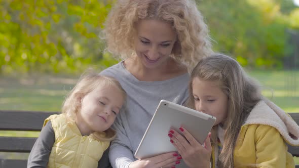 Close-up of Smiling Caucasian Woman with Blond Curly Hair Sitting on the Bench in the Autumn Park