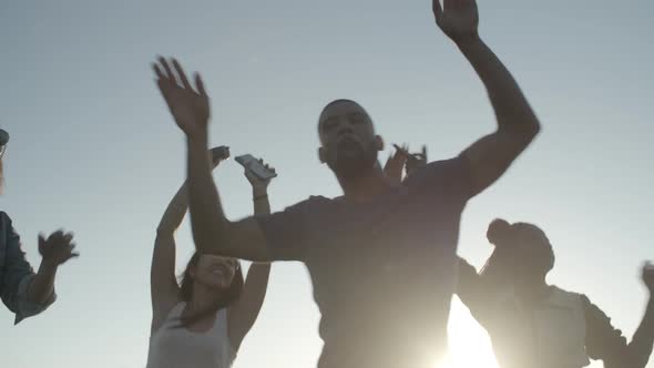 Smiling Young People Dancing with Raised Hands in Park