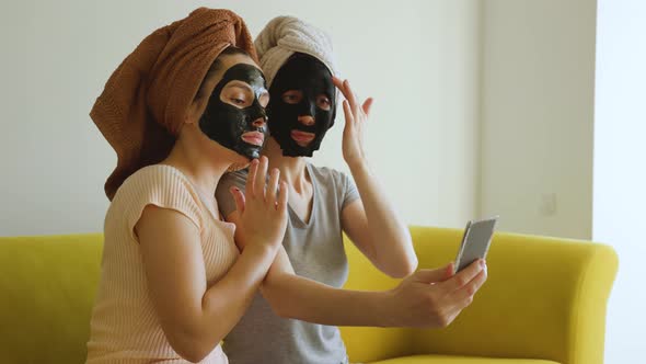 Two Girls with a Towel on Their Head and a Black Skin Care Mask