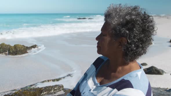 Senior woman sitting on a rock at the beach