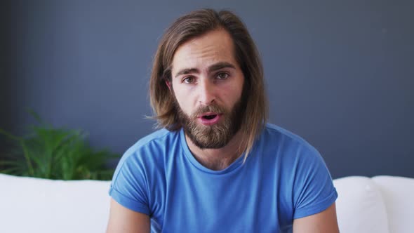 Portrait of caucasian man talking on videocall while sitting on the couch at home