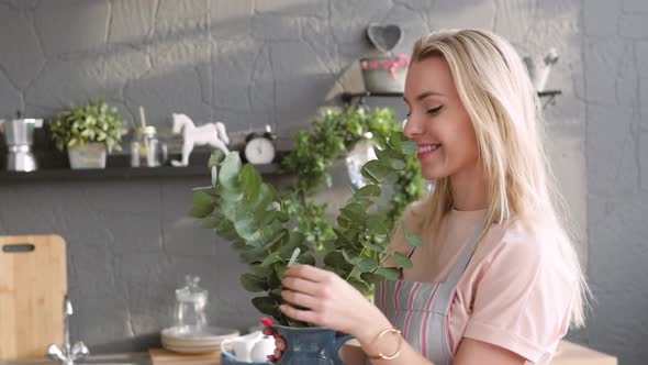 Joyful Woman Makes a Bouquet for Table Setting. The Blonde Is Making a Bouquet of Eucalyptus