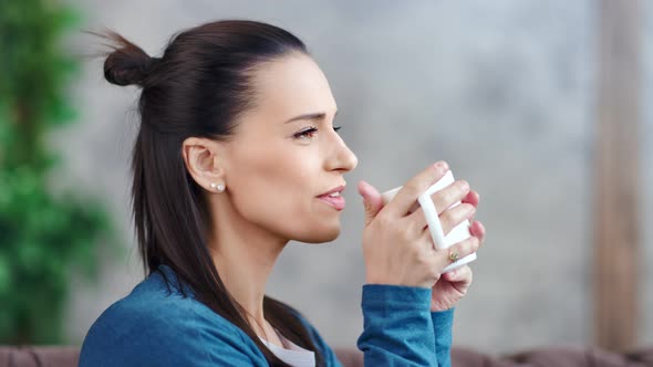 Attractive Smiling Young Brunette Woman Dreaming and Drinking Hot Beverage Medium Closeup