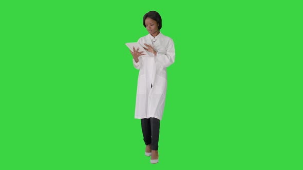 African American Female Doctor Holding a Tablet Computer While Walking on a Green Screen, Chroma Key