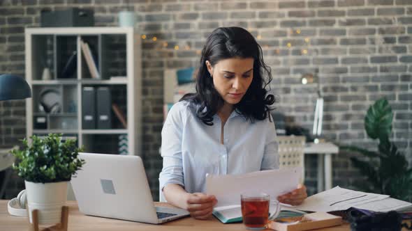 Worried Manager Using Laptop and Reading Paper Document Working in Office Alone