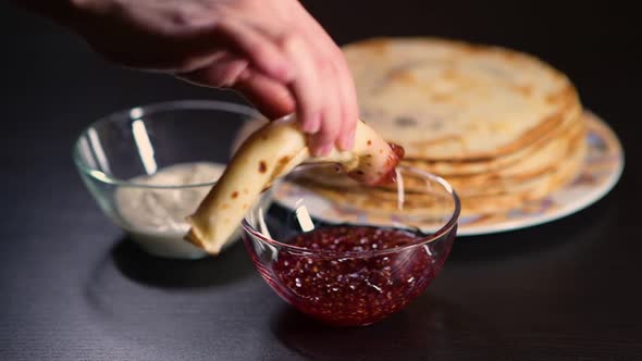 girl's hand dunks pancake in jam