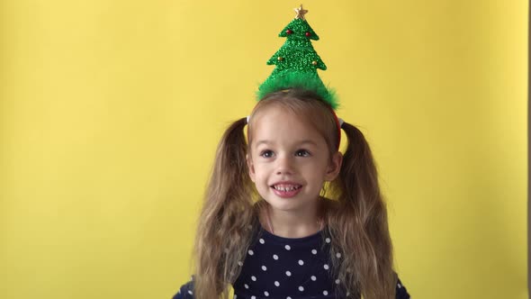 Portrait Emotion Cute Happy Preschool Baby Girl With Ponytail And Christmas Tree on Head Smiling