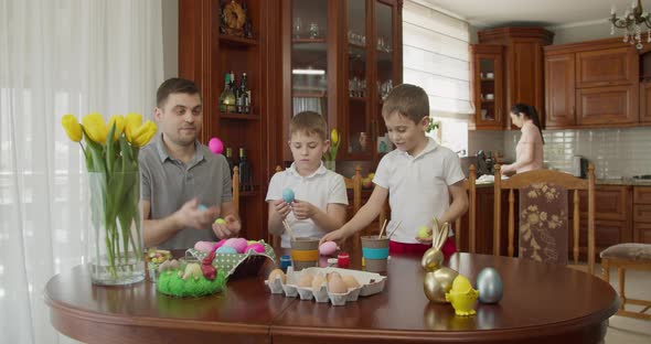 Father with Two Boys Juggles Colored Eggs My Mother Does Chores in the Kitchen