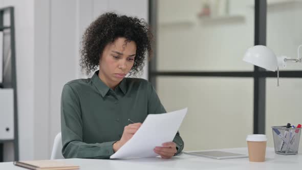 African Woman Reading Papers at Work