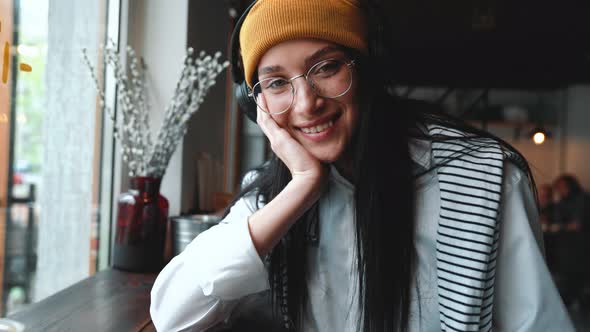 Handsome young brunette woman wearing hat and eyeglasses looking at the camera