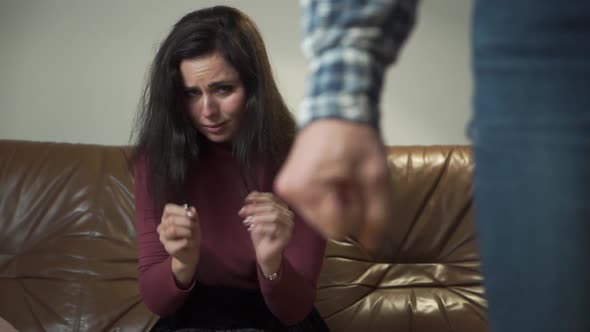 Portrait of a Frightened To Death Caucasian Woman Sitting at the Couch with Ring and Hiding Her Face