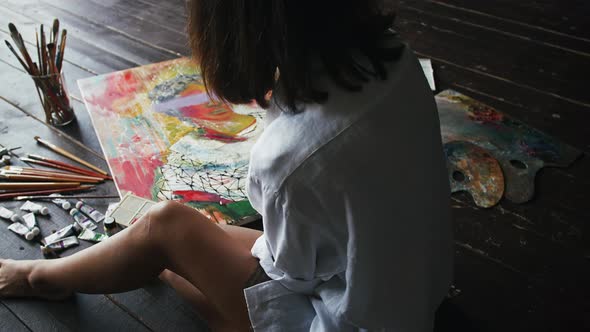 Unrecognizable Woman Painter is Drawing a Portrait on Canvas in Modern Art Style While Sitting on