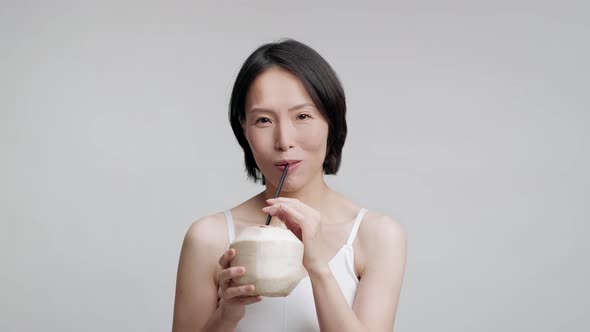 Mature Japanese Woman Drinking Coconut Water With Straw Gray Background