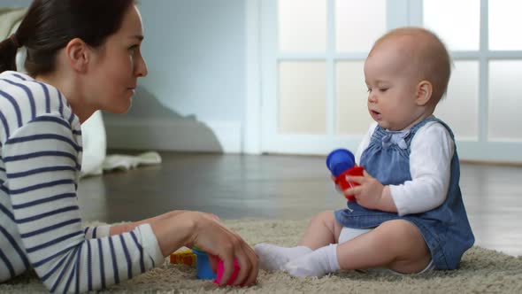 Happy Mother Entertaining her Baby Daughter